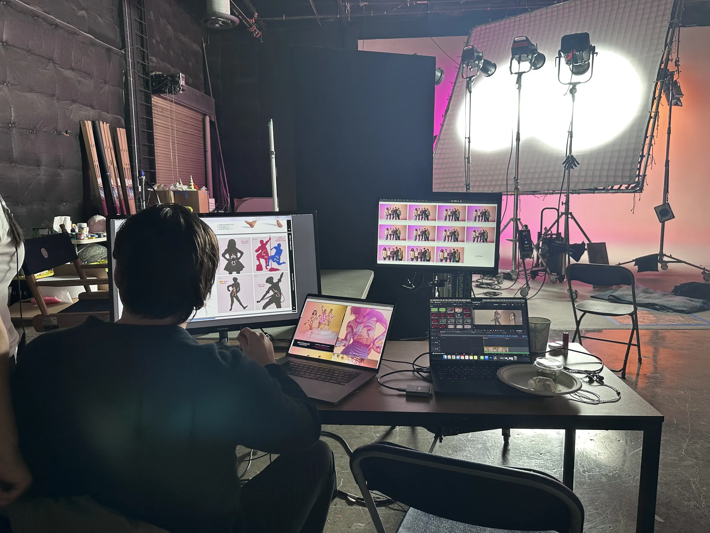 Three-screen workflow — catalog layout on external monitor, Weissman website on MacBook, Capture One tethered feed on second laptop, pink set in background